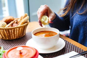 Woman Dipping Lime Into Bowl of Soup