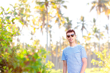 Portrait of a Brazilian man wearing sunglasses, looking at the camera. In the background, there are...