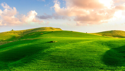 scenery rural view of a contryside farm in green fields and hills with amazing cloudy sky on background