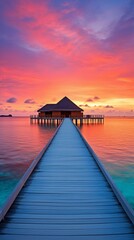 Obraz premium Serene of overwater bungalow connected by a boardwalk set against a stunning sunset with vibrant pink and orange hues colours 
