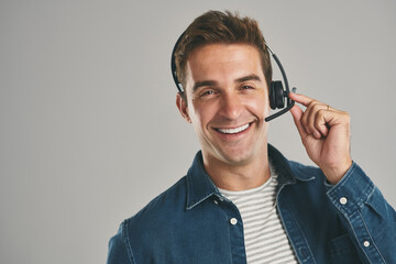 Man, portrait and headset for call centre telemarketing on grey background in studio, contact us or...