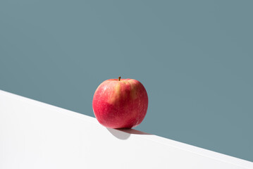 Una manzana roja sobre un soporte blanco y fondo verde