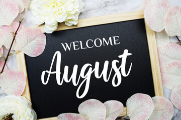 Welcome August text message with eucalyptus leaf decoration on marble background