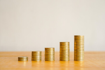 Upward financial growth stack of golden money coin on wooden desk with copy space. Business and financial concept background. 