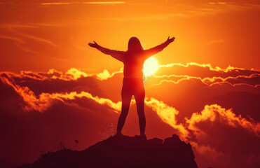 Silhouette of a person standing with arms outstretched at sunrise atop a mountain