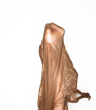 A fist breaking through a brown plastic grocery bag against a white background