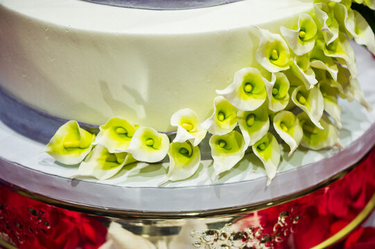 Closeup of a white wedding cake with Calla Lily decorations along the side