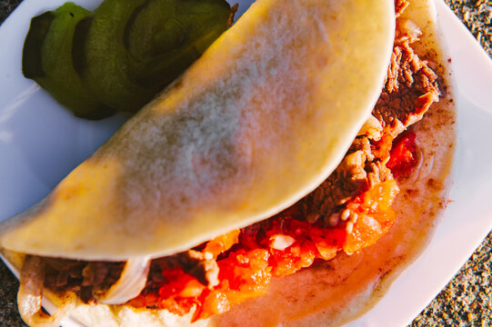 Closeup of a handmade tortilla taco filled with beef, onions and tomato at a wedding picnic