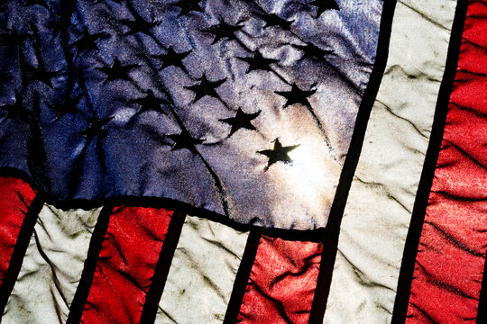 Light from a partial solar eclipse shining through a synthetic American flag, detail