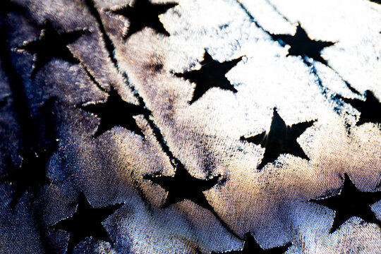 Light from a partial solar eclipse shining through a synthetic American flag, detail