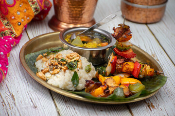 Air fried vegan barbeque  seitan and vegetables skewers served on banana leaf along with Indian pongal and sambar