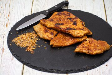 Vegan seitan schitzel slices on slate plate, cut steak style