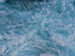 Aerial photo of a sea water surface. Turquoise blue water with white foam on waves - view from above. Stylized background abstract texture photo. Tenerife, Puerto de la Cruz