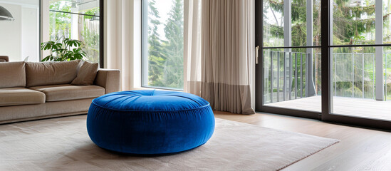 Elegant blue velvet pouf in a minimalist living room with neutral tones and large windows, enhancing the overall aesthetic and comfort