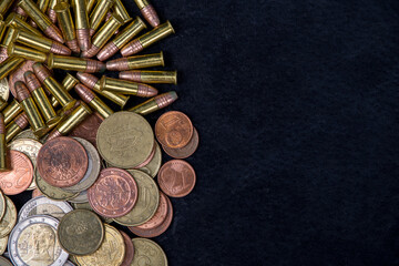 a pile of gold coins and a bullet on black. Copy space.