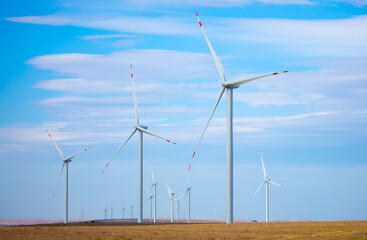 Fleet of power generators in motion. The blades of the wind farm rotate against the sky. The concept of extracting electricity from renewable sources. Wind turbine to generate electricity.