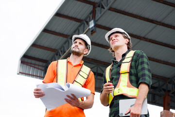 Engineer wearing safety helmet stands smiling at construction site.