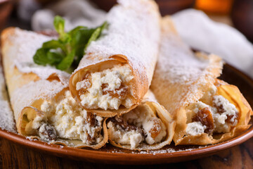 Thin pancakes filled with cottage cheese, honey and raisins, rolled in the form of a tube,...