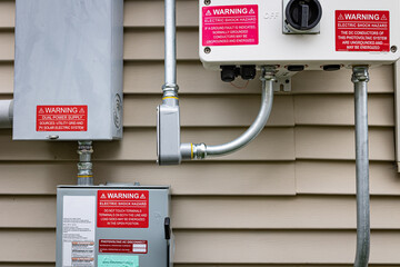 Close-up view of electricity boxes installed on the exterior of a single-family house: photovoltaic...