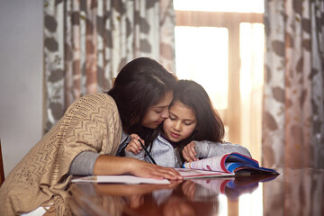 Mother, kid and homework with book on table for learning, knowledge or support in education. Happy,...