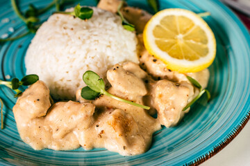 Fricassee with rice on a turquoise plate with micro greens and lemon