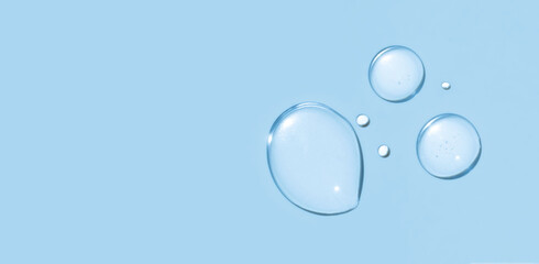 round drops of transparent gel serum on blue background
