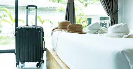 Travel bag in hotel room,Black Luggage and hat in modern hotel room with windows, curtains and bed....