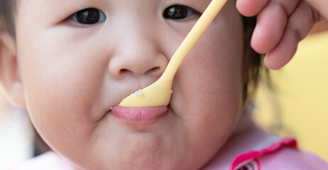 Child eating rice with a spoon close-up,Close up infant baby feeding food on the kid chair