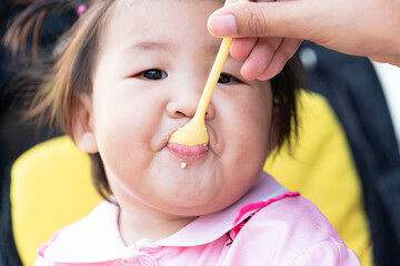 Child eating rice with a spoon close-up,Close up infant baby feeding food on the kid chair