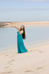 A violinist plays on a sandy beach in a long dress. Asian woman with long hair plays the violin on the beach
