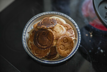 A bowl of pancakes with smiley faces, steaming hot and ready to eat. This playful and delicious breakfast is perfect for brightening up a morning and bringing joy to the family table.
