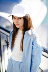 Cute teenage girl 10 - 12 year old wearing cap and blue shirt over sea background outdoor. Summer...