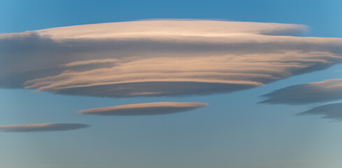 White lenticular clouds in the blue sky