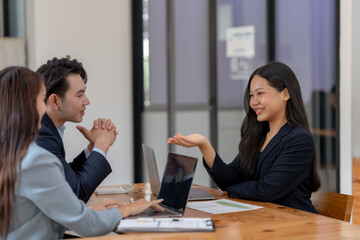 Business meeting with three professionals discussing ideas in a modern office, showcasing teamwork, collaboration, and professional interaction.