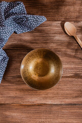 flat lay mock up of empty golden bowl over rustic wooden table with spoon and flowered cloth