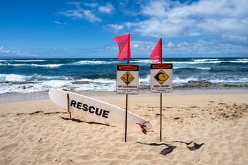 Tropical beach with gold sand and blue waters of the Pacific Ocean, ocean safety warning signs and...