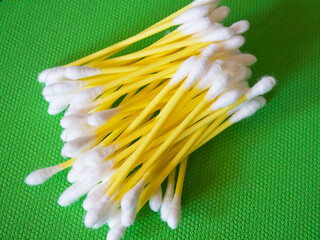 Personal Care. Cotton swabs for hygiene, arranged on green.