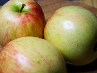 Fresh Apple Trio. Three apples with red and green hues on a wooden surface, conveying natural freshness.
