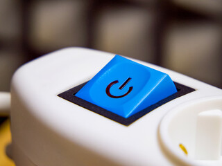 Blue power button with a symbol on white machinery, representing action and response.