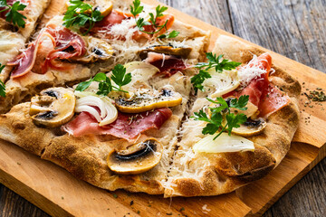 Roman Pizza with mozzarella cheese, cured ham and mushrooms on wooden table
