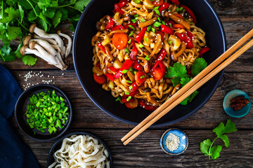 Asian style stir fried vegetables and noodles on wooden table
