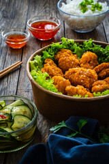 Takeaway food - fried breaded chicken nuggets and vegetables on wooden table
