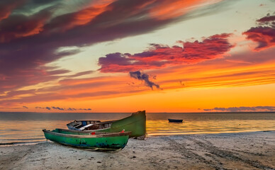 Coastal landscape at dawn with anchored fishing boats on sandy beach of the Baltic Sea. 