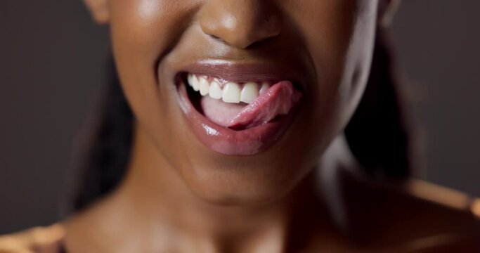 Tongue, mouth and woman in closeup with licking lips for dental care and oral hygiene in studio. Female person, smile and beauty for tooth wellness and teeth whitening treatment on dark background