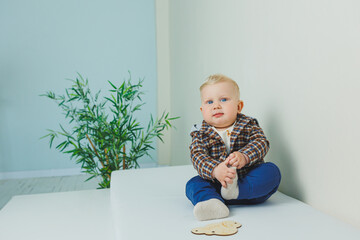 A small baby with blue eyes in stylish clothes. A boy in a shirt and blue pants. Children's stylish...