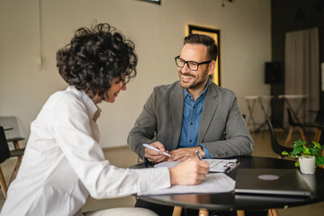 Mature woman sign insurance or contract to adult man in cafe