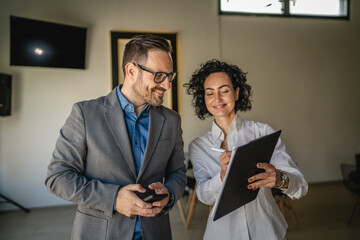 Colleagues stand in cafe woman hold document and man hold mobile phone