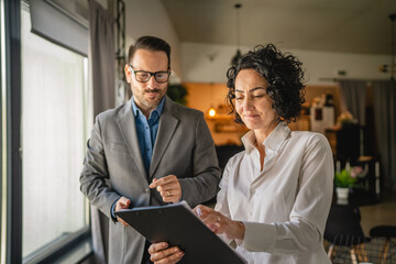 Colleagues stand in cafe woman hold document and man hold mobile phone