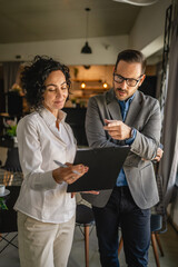 Colleagues stand in cafe woman hold document and man hold mobile phone