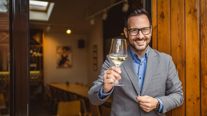 Portrait of adult man sommelier stand in front of winery and hold wine